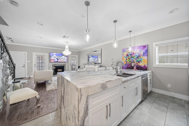 kitchen with white cabinets, dishwasher, light stone counters, open floor plan, and a sink