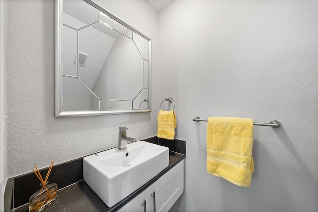 bathroom featuring a textured wall, visible vents, and vanity