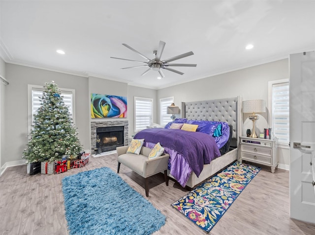 bedroom with a fireplace with flush hearth, crown molding, baseboards, and wood finished floors