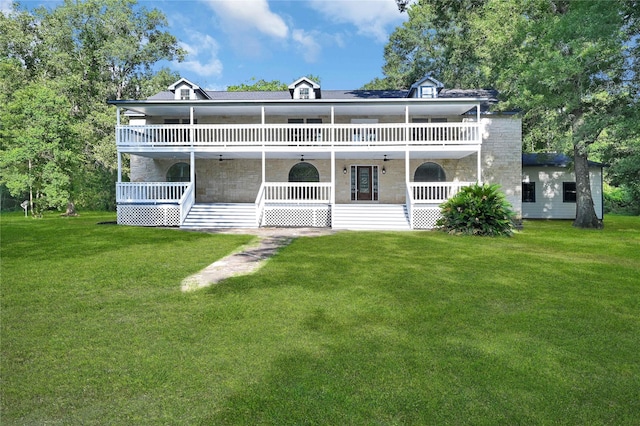 back of property featuring covered porch, stairs, stone siding, and a yard