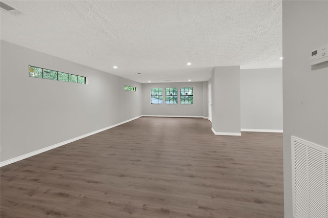 empty room with dark wood-style floors, recessed lighting, visible vents, and baseboards