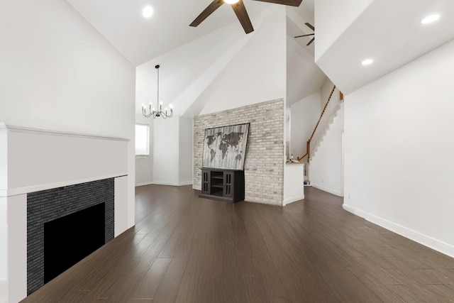 unfurnished living room with a fireplace, baseboards, dark wood finished floors, and ceiling fan with notable chandelier