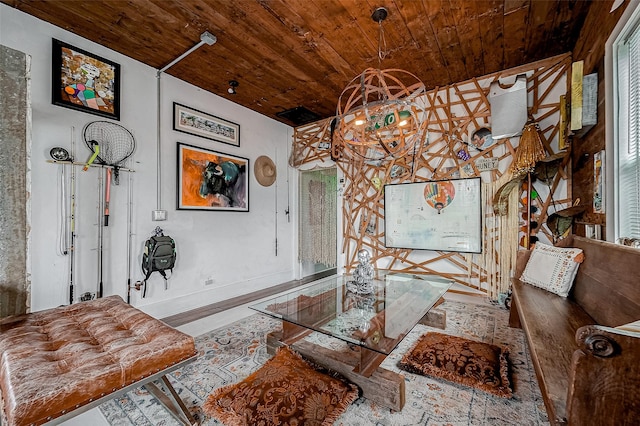 living area featuring baseboards, wooden ceiling, and an inviting chandelier