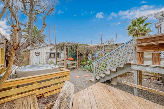 view of yard featuring a jacuzzi, stairs, fence, and a deck