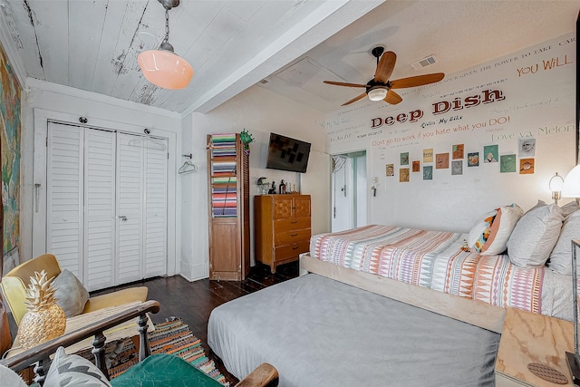 bedroom with wooden ceiling, dark wood-type flooring, visible vents, a ceiling fan, and a closet