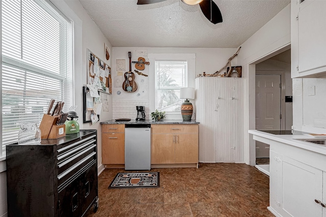 kitchen featuring dark countertops, ceiling fan, stainless steel refrigerator, a textured ceiling, and light brown cabinetry