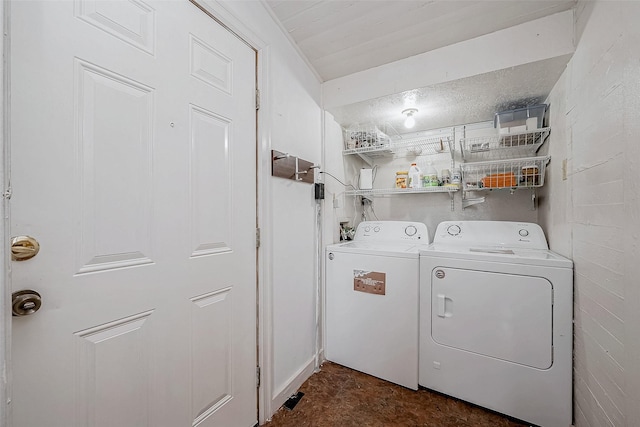 laundry room with washing machine and clothes dryer and concrete block wall