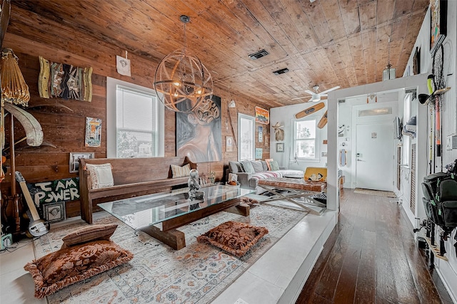 living room with a chandelier, wooden ceiling, wood walls, wood finished floors, and visible vents