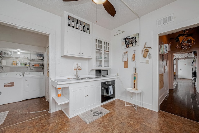 kitchen with visible vents, white cabinetry, black oven, open shelves, and washing machine and clothes dryer