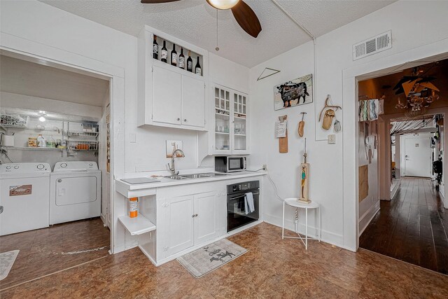 912 Broadway St, Galveston, TX 77550 - kitchen featuring open shelves, stainless steel microwave, black oven, visible vents, and washer and dryer