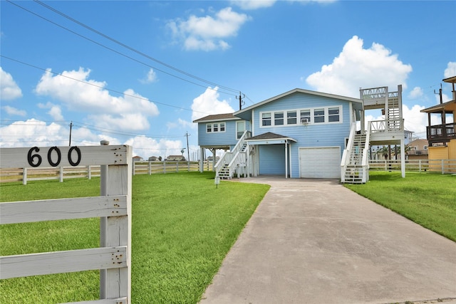 coastal home with stairs, concrete driveway, and a front lawn