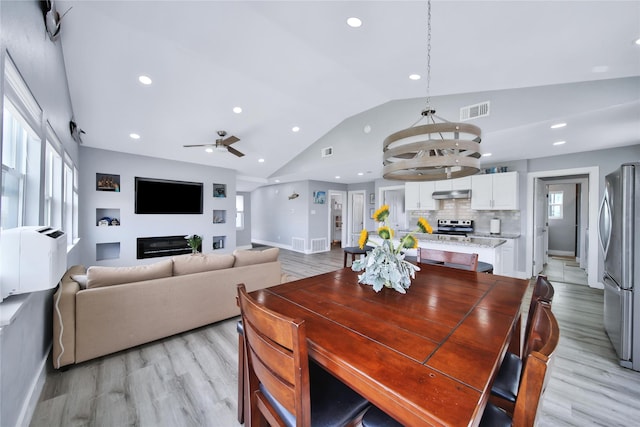 dining space with vaulted ceiling, light wood-type flooring, visible vents, and a healthy amount of sunlight