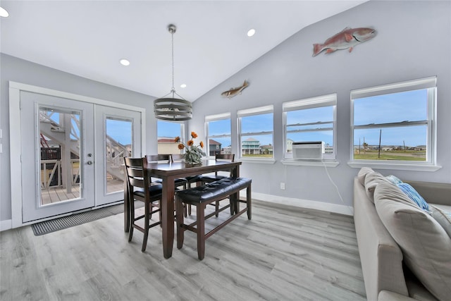 dining room featuring lofted ceiling, french doors, light wood-style floors, and a healthy amount of sunlight