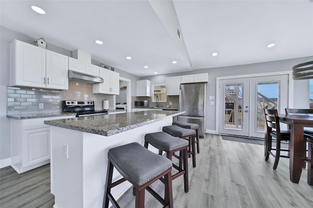 kitchen with decorative backsplash, appliances with stainless steel finishes, a center island, under cabinet range hood, and white cabinetry