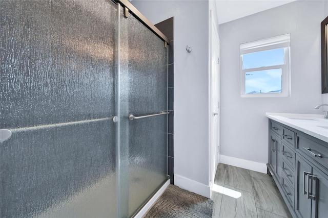 bathroom featuring an enclosed shower, vanity, and baseboards