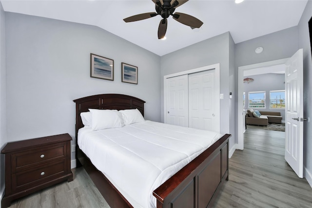 bedroom with lofted ceiling, ceiling fan, a closet, and light wood-style floors