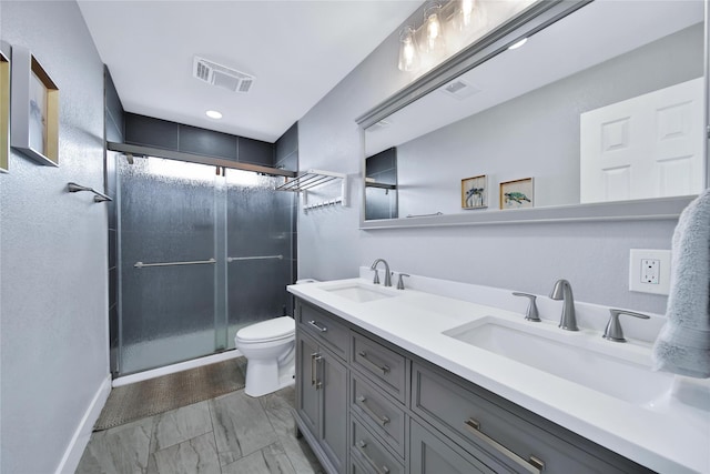 bathroom with a stall shower, a sink, toilet, and double vanity