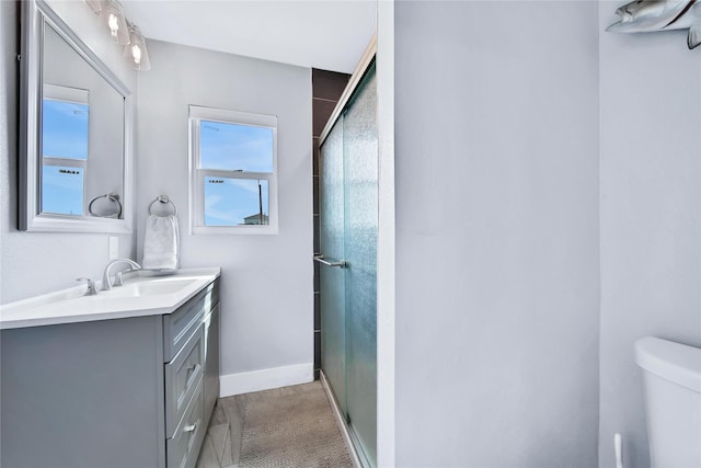 full bath featuring a stall shower, vanity, toilet, and baseboards