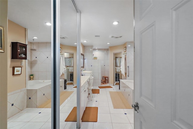 bathroom featuring a garden tub, tile walls, visible vents, vanity, and tile patterned floors