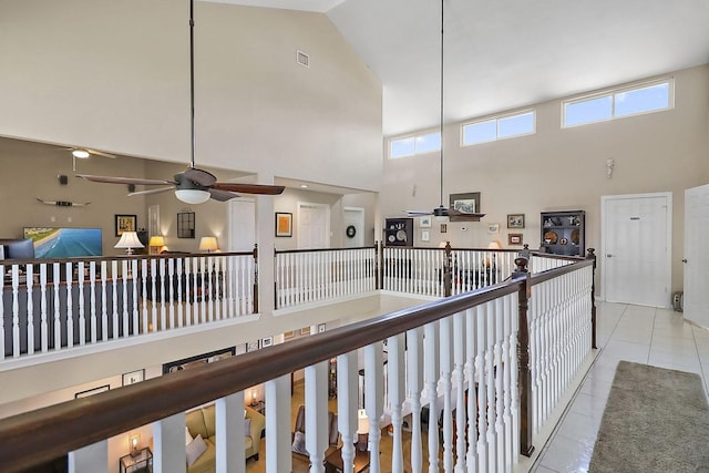 hallway with light tile patterned floors, a high ceiling, an upstairs landing, and visible vents