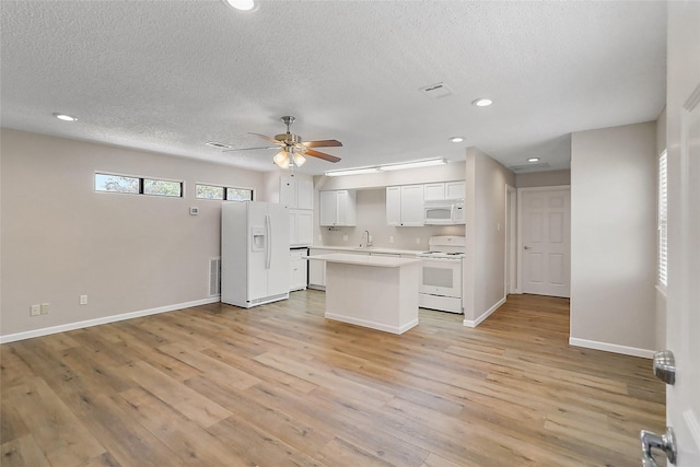 kitchen featuring white appliances, visible vents, white cabinets, light countertops, and light wood-type flooring