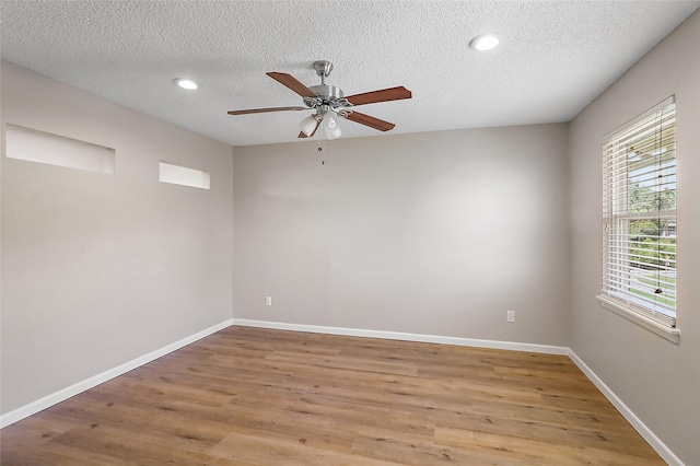 spare room with ceiling fan, a textured ceiling, light wood-style flooring, and baseboards