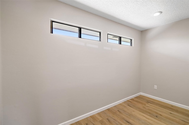 spare room featuring a textured ceiling, baseboards, and wood finished floors