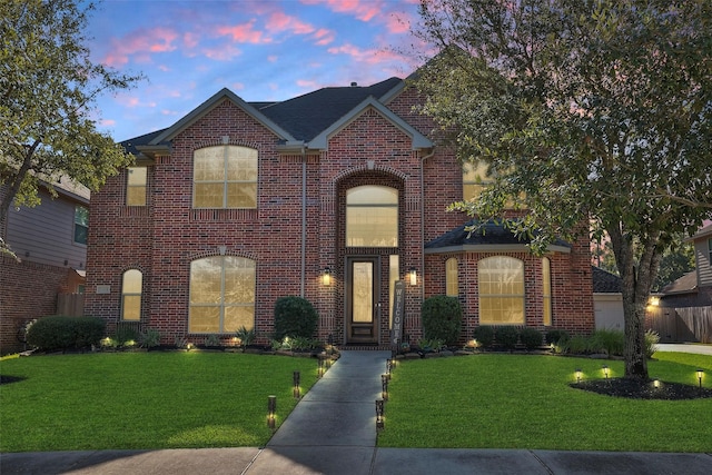 view of front facade featuring an attached garage, a front lawn, and brick siding