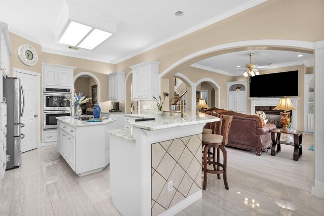55 Monterrey Rd E, Montgomery, TX 77356 - kitchen featuring stainless steel appliances, arched walkways, ceiling fan, a kitchen breakfast bar, and a peninsula