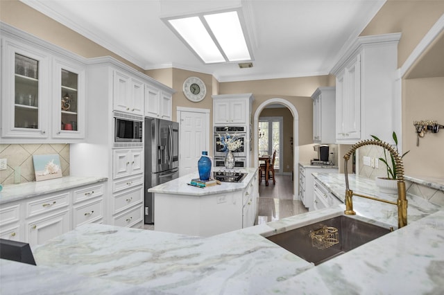 55 Monterrey Rd E, Montgomery, TX 77356 - kitchen with appliances with stainless steel finishes, a sink, arched walkways, light stone counters, and white cabinets