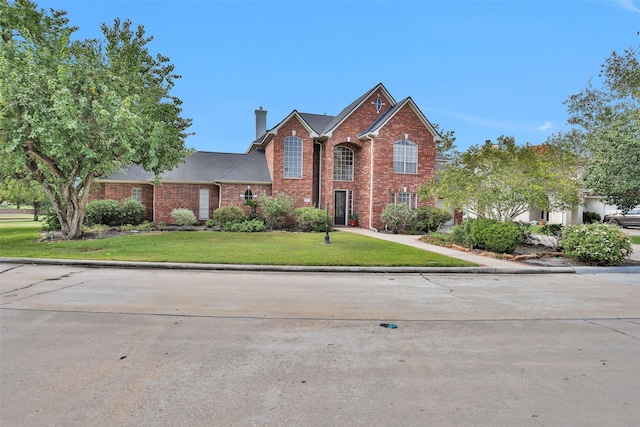 traditional-style home featuring brick siding, a chimney, and a front yard