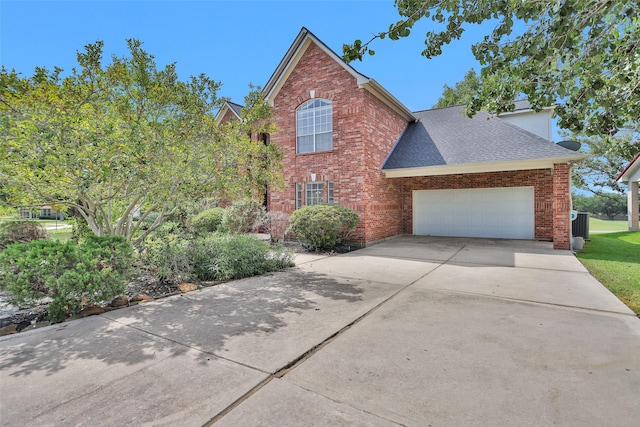 view of side of home with a garage, driveway, brick siding, and roof with shingles