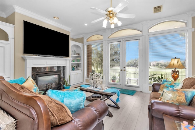 living area featuring built in features, a high end fireplace, visible vents, and crown molding