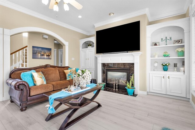 55 Monterrey Rd E, Montgomery, TX 77356 - living area featuring a fireplace, light wood-style floors, ornamental molding, a ceiling fan, and arched walkways