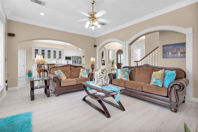 living area with ceiling fan, light wood-style flooring, visible vents, and crown molding