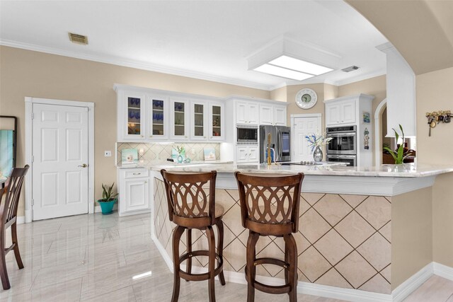 55 Monterrey Rd E, Montgomery, TX 77356 - kitchen with stainless steel appliances, arched walkways, a breakfast bar area, decorative backsplash, and white cabinets