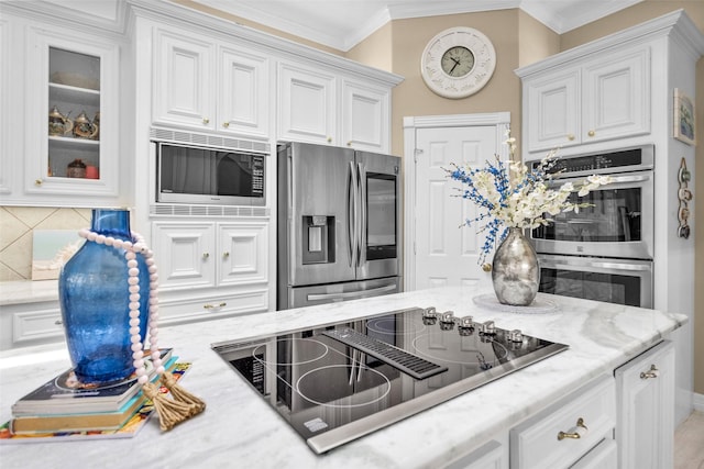 kitchen featuring light stone counters, white cabinetry, ornamental molding, appliances with stainless steel finishes, and backsplash