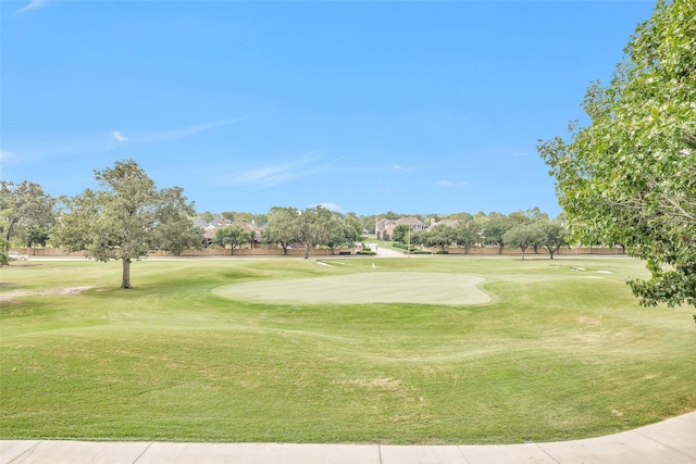 surrounding community with golf course view and a yard