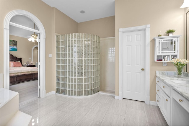 bathroom featuring a ceiling fan, connected bathroom, vanity, a walk in shower, and baseboards