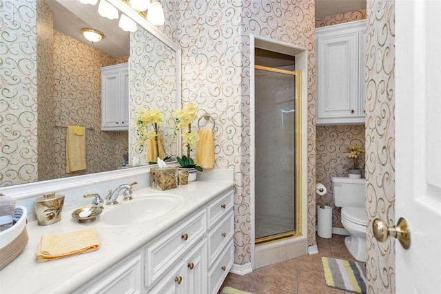 bathroom featuring tile patterned flooring, toilet, vanity, a shower stall, and wallpapered walls