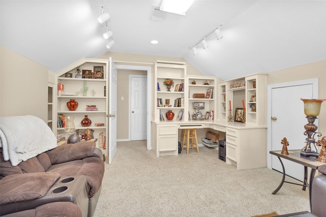 interior space featuring light carpet, visible vents, vaulted ceiling, built in study area, and rail lighting