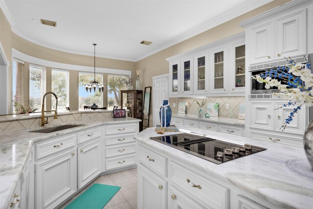 55 Monterrey Rd E, Montgomery, TX 77356 - kitchen with black electric stovetop, a sink, decorative backsplash, a chandelier, and white cabinetry
