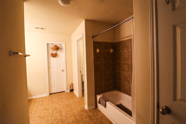 full bathroom featuring visible vents, baseboards, a textured ceiling, and washtub / shower combination