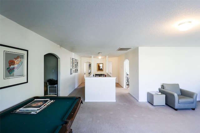 rec room with carpet flooring, visible vents, arched walkways, and a textured ceiling