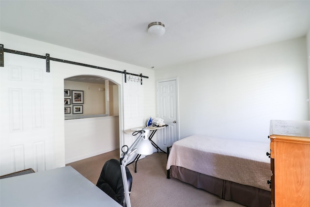 bedroom featuring a barn door, arched walkways, and carpet floors