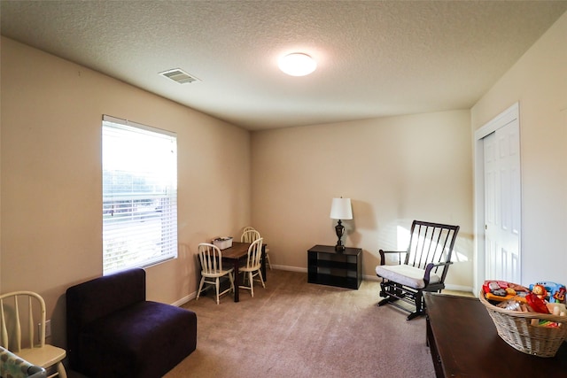 living area with baseboards, carpet, visible vents, and a textured ceiling