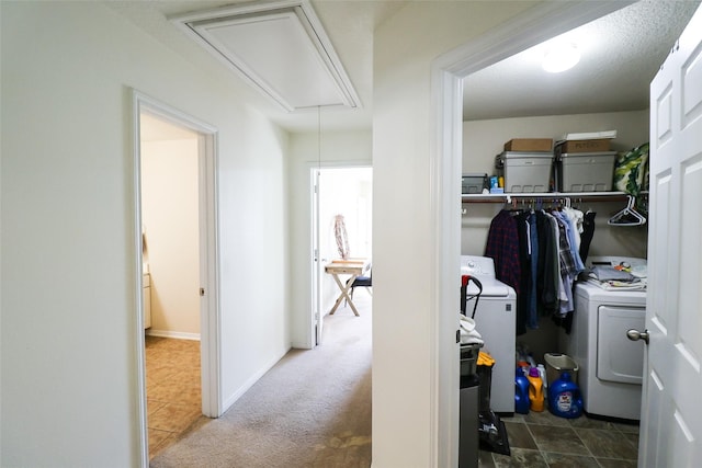 corridor featuring attic access, baseboards, carpet floors, and washing machine and clothes dryer