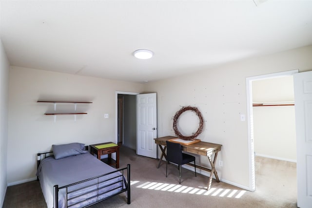 bedroom featuring a spacious closet, carpet, and baseboards