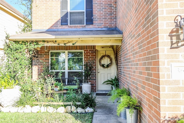 doorway to property with a porch and brick siding