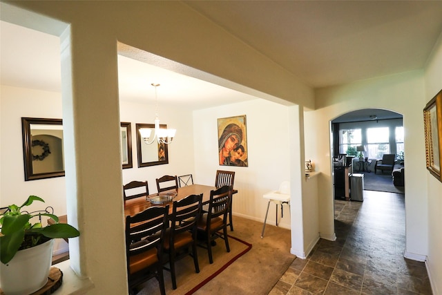 dining area featuring an inviting chandelier, stone finish floor, and baseboards